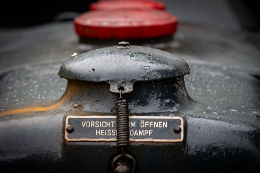 Metallschild an einem alten Traktor, auf dem steht: Vorsicht beim Öffnen, heißer Dampf